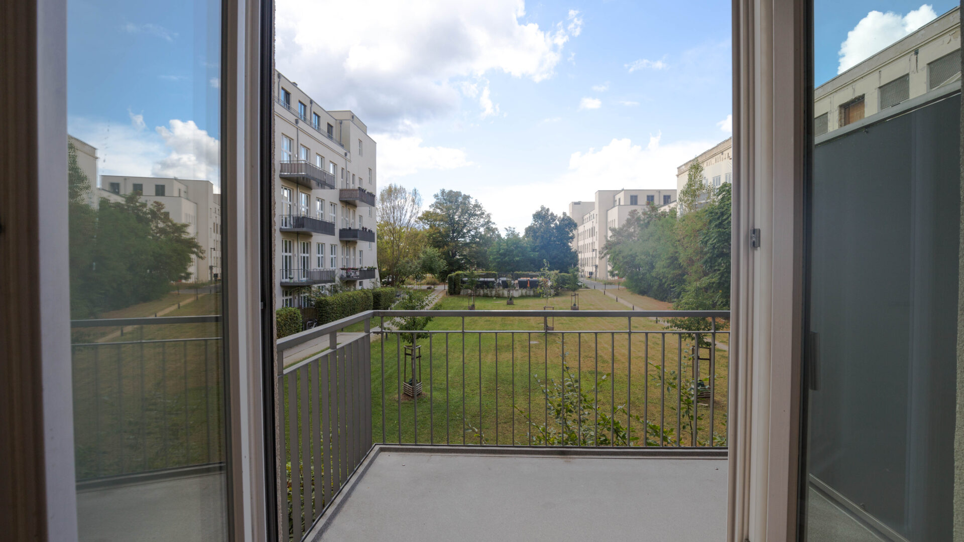 Ausblick vom Balkon in eine begrünte Hofanlage von einem Wohnobjekt in Berlin-Lichterfelde.