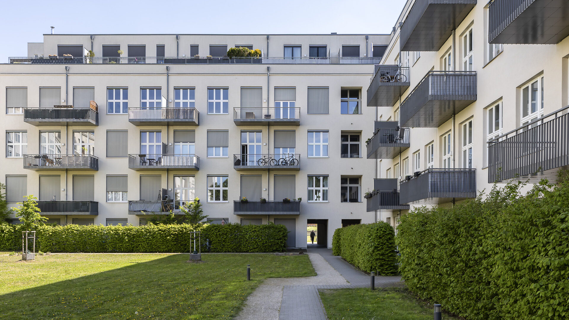 Moderne Fassade eines 4-stöckigen Wohngebäudes mit großen Fenstern und Balkonen in einem grünem Umfeld in Berlin-Lichterfelde.
