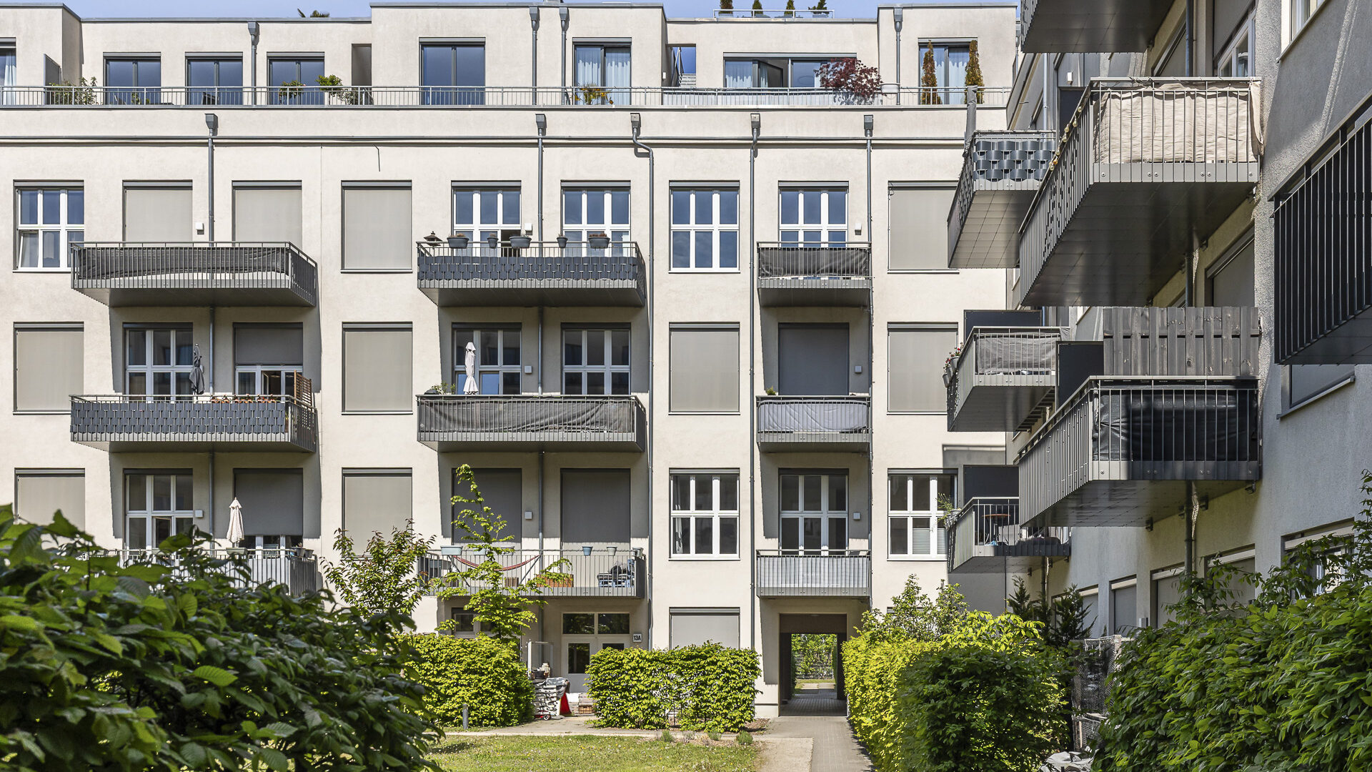 Moderne Fassade eines 4-stöckigen Wohngebäudes mit großen Fenstern und Balkonen in einem grünem Umfeld in Berlin-Lichterfelde.
